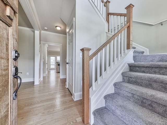 foyer entrance with crown molding and light hardwood / wood-style flooring