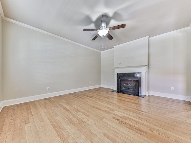 unfurnished living room with a premium fireplace, ornamental molding, light hardwood / wood-style flooring, and ceiling fan