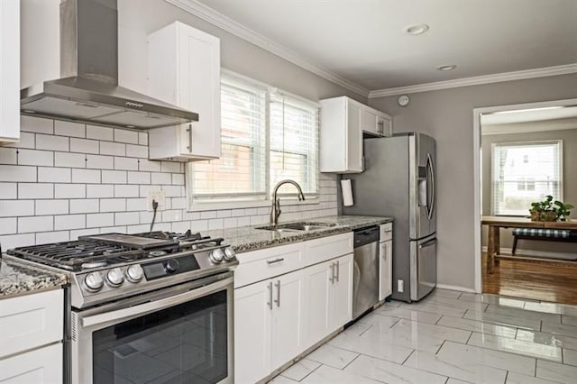 kitchen featuring wall chimney range hood, sink, stainless steel appliances, white cabinets, and stone countertops