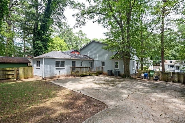 rear view of property with a wooden deck, central AC unit, and a patio area