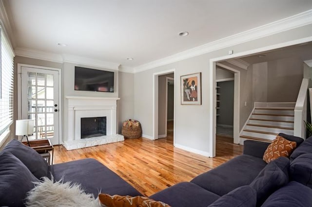 living room featuring hardwood / wood-style flooring, ornamental molding, and a fireplace