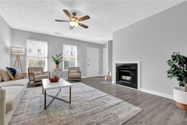 living room featuring ceiling fan, wood-type flooring, and a textured ceiling