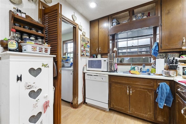kitchen featuring white appliances, a sink, washer / dryer, open shelves, and light wood-style floors