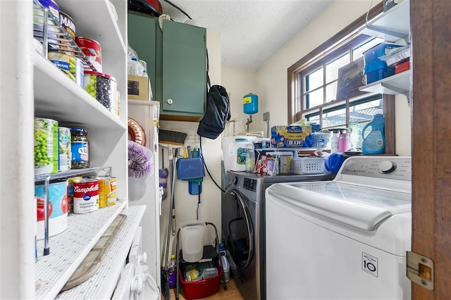 clothes washing area featuring separate washer and dryer, cabinet space, and a textured ceiling
