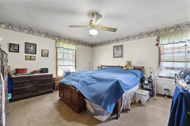 bedroom with light colored carpet, a textured ceiling, a ceiling fan, and multiple windows