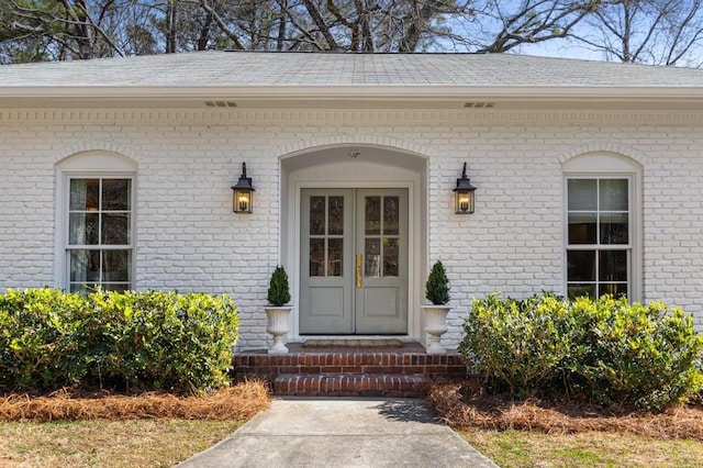 property entrance featuring brick siding and roof with shingles