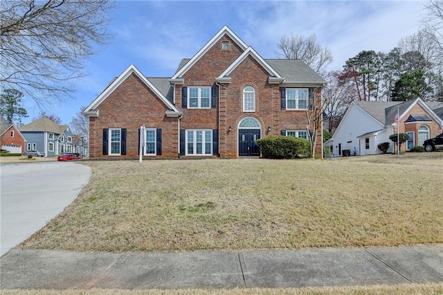 colonial inspired home with brick siding and a front yard