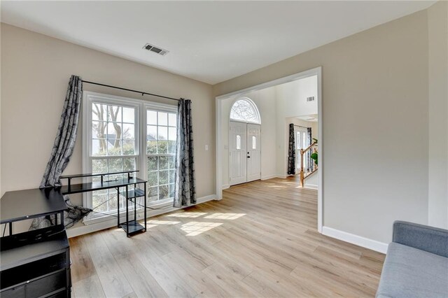 foyer entrance featuring stairs, baseboards, visible vents, and light wood-type flooring