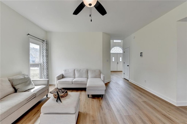 living room with a ceiling fan, light wood-type flooring, and baseboards