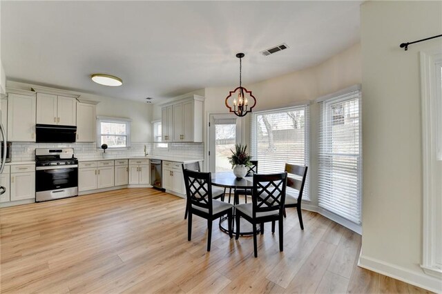 kitchen with tasteful backsplash, visible vents, dishwashing machine, light wood-style flooring, and gas stove