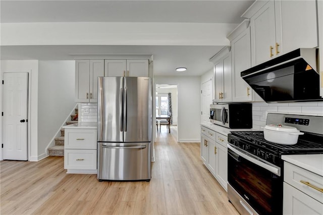 kitchen with light wood finished floors, stainless steel appliances, decorative backsplash, light countertops, and exhaust hood