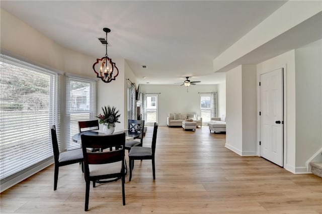 dining room featuring visible vents, baseboards, stairs, light wood-style flooring, and ceiling fan with notable chandelier