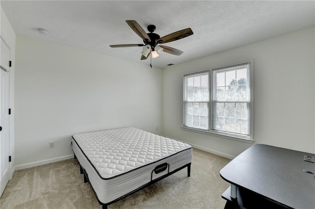 bedroom with light carpet, ceiling fan, a textured ceiling, and baseboards