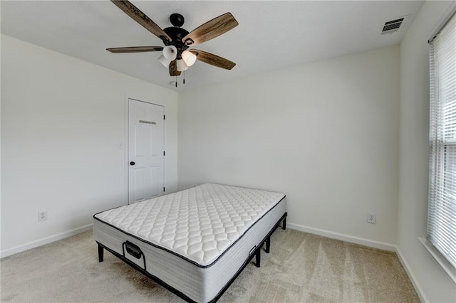 bedroom with visible vents, light colored carpet, baseboards, and ceiling fan