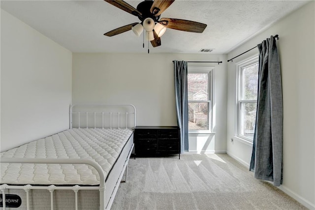 unfurnished bedroom featuring visible vents, ceiling fan, baseboards, light carpet, and a textured ceiling