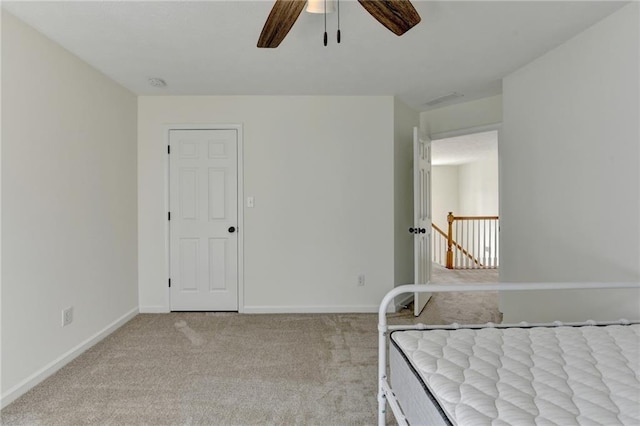 unfurnished bedroom featuring carpet flooring, visible vents, a ceiling fan, and baseboards