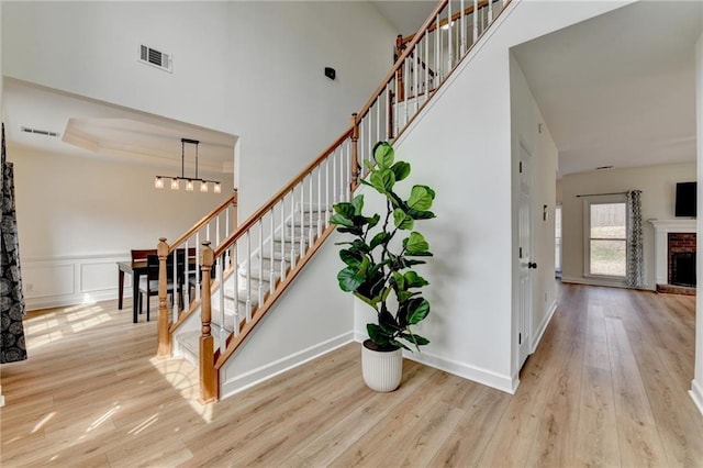 stairway featuring visible vents, a fireplace, a high ceiling, and wood finished floors