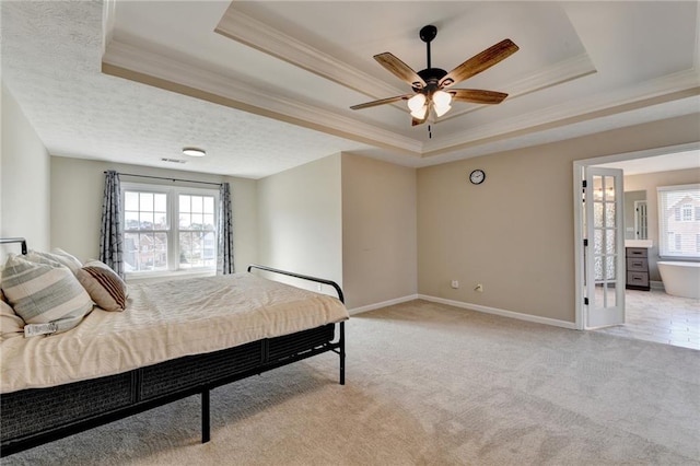 bedroom with a raised ceiling, multiple windows, and light colored carpet