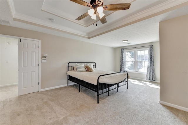 carpeted bedroom with a raised ceiling, crown molding, baseboards, and ceiling fan