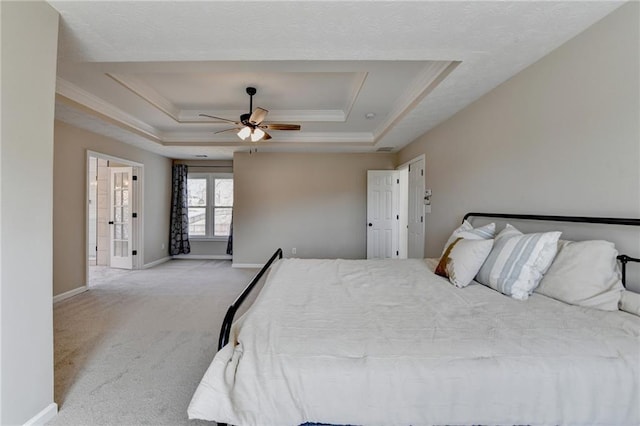 carpeted bedroom with a raised ceiling, crown molding, and baseboards