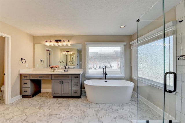 full bath with vanity, baseboards, a freestanding bath, a shower stall, and toilet