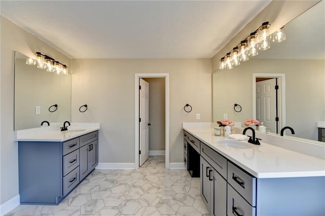 bathroom with two vanities, baseboards, and a sink