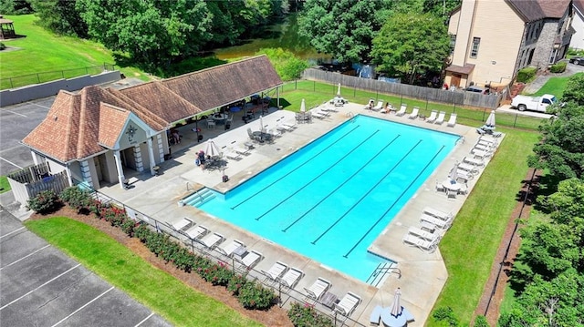 pool featuring a patio area, a lawn, and fence