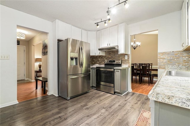 kitchen with stainless steel appliances, under cabinet range hood, light countertops, and tasteful backsplash