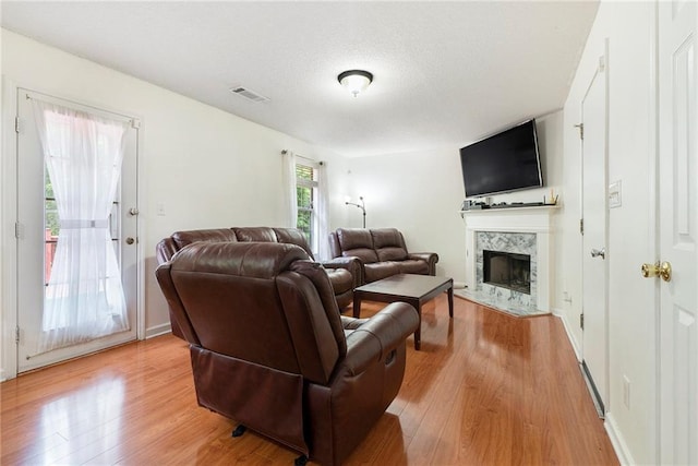 living room featuring light wood finished floors, a premium fireplace, and a textured ceiling