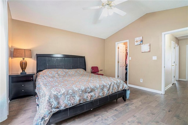 bedroom with lofted ceiling, wood finished floors, baseboards, a walk in closet, and ceiling fan