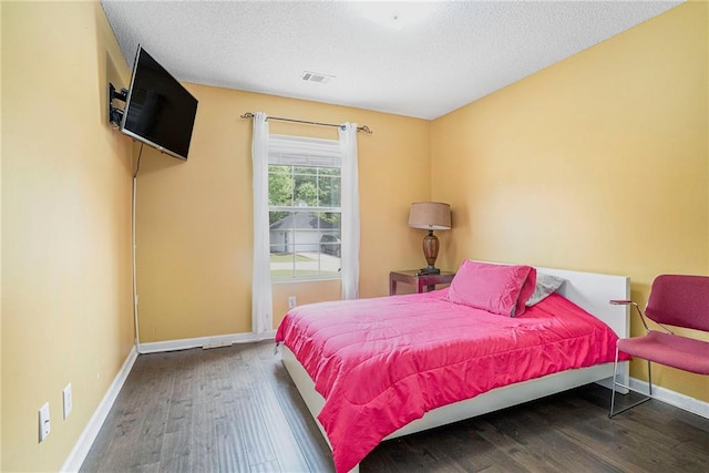 bedroom featuring wood finished floors, baseboards, and a textured ceiling