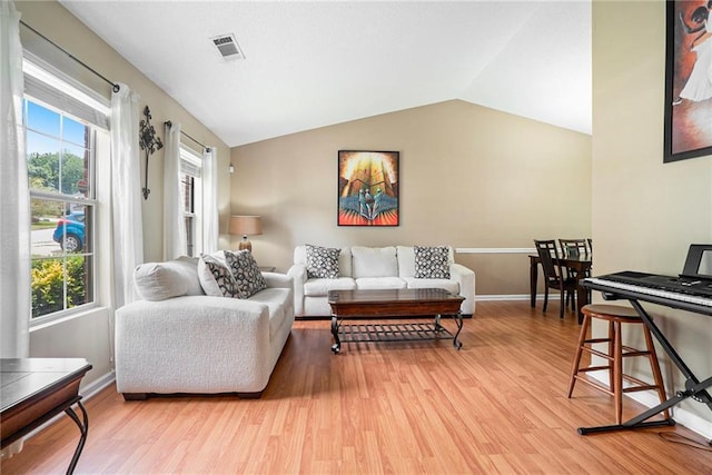 living area with light wood-style flooring, lofted ceiling, and baseboards