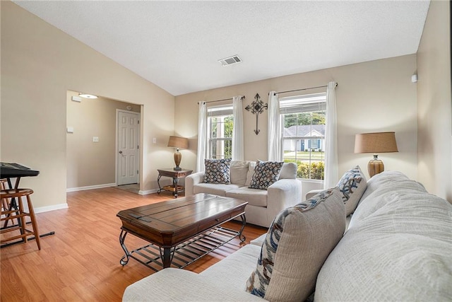 living area with light wood finished floors, vaulted ceiling, and baseboards