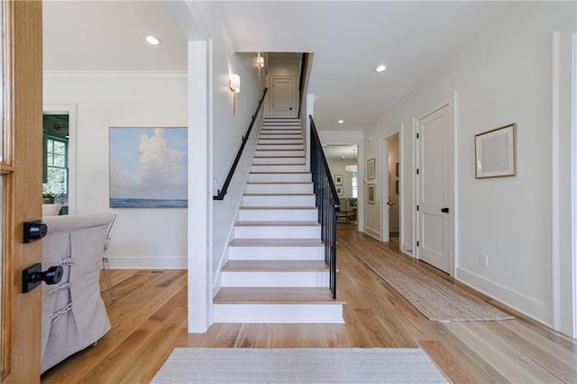 stairway with recessed lighting, wood finished floors, baseboards, and ornamental molding