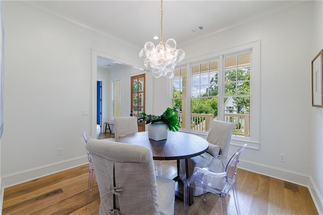 dining area with visible vents, crown molding, baseboards, wood finished floors, and a notable chandelier
