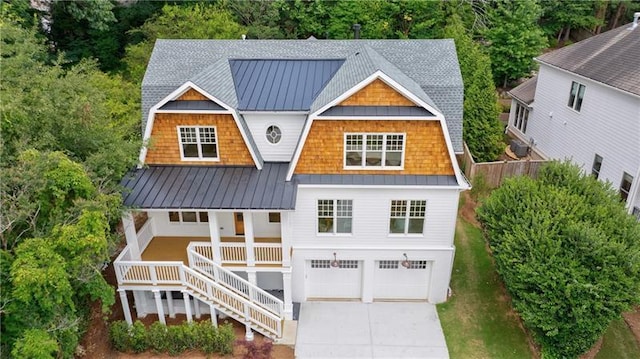 view of front facade with a gambrel roof, stairs, covered porch, metal roof, and a standing seam roof