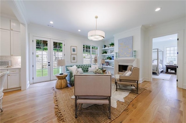 living room featuring a fireplace, french doors, light wood finished floors, and ornamental molding