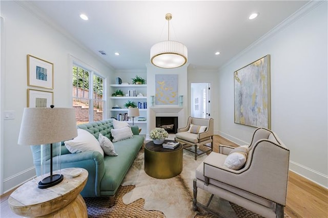 living room featuring wood finished floors, recessed lighting, a fireplace, crown molding, and baseboards
