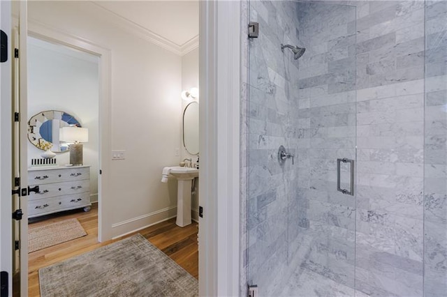 full bath featuring a shower stall, crown molding, baseboards, wood finished floors, and a sink