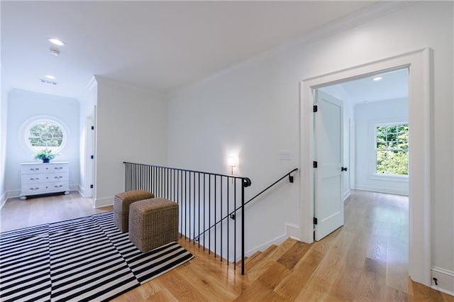 hallway with baseboards, an upstairs landing, light wood-style floors, and crown molding