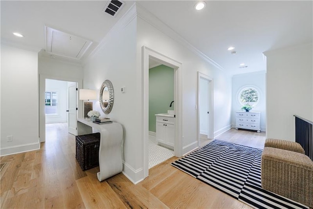 hallway featuring visible vents, attic access, light wood-style flooring, recessed lighting, and ornamental molding
