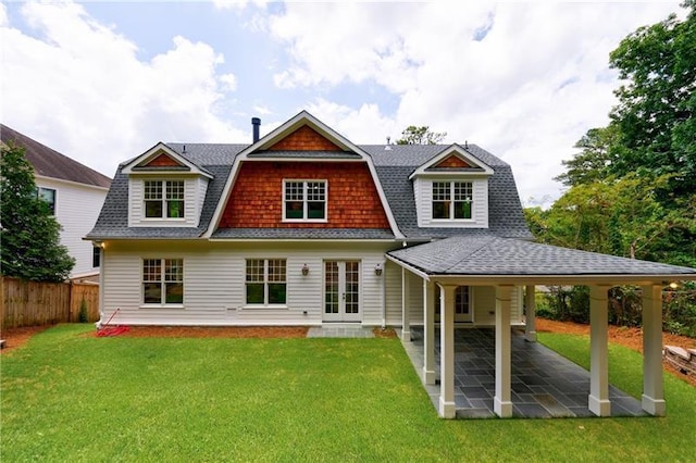 rear view of house featuring a patio area, a gambrel roof, a lawn, and fence