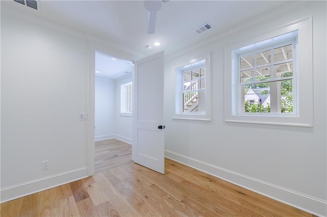 spare room featuring crown molding, light wood-style flooring, baseboards, and visible vents