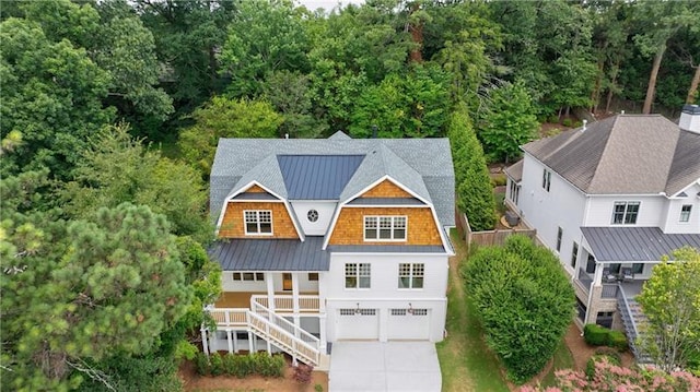 view of front of home featuring a gambrel roof, a standing seam roof, stairway, concrete driveway, and metal roof