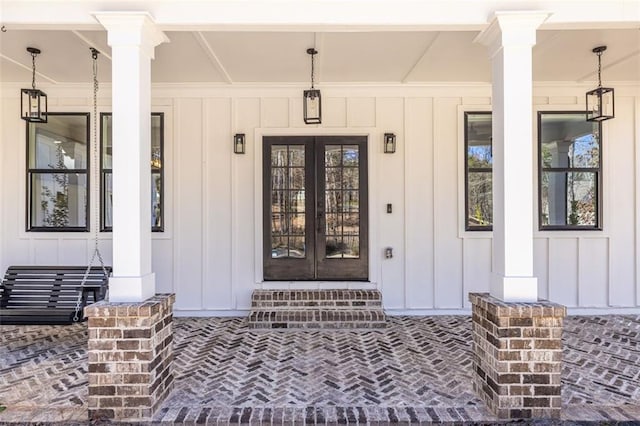 entrance to property with covered porch, board and batten siding, and french doors