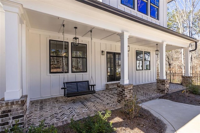 view of exterior entry featuring french doors, a porch, and board and batten siding