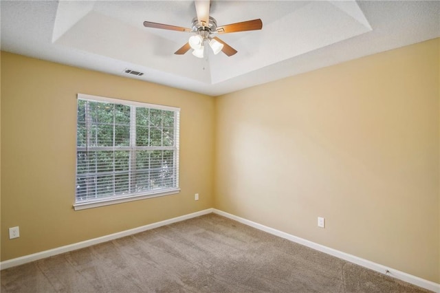 carpeted empty room featuring a raised ceiling and ceiling fan