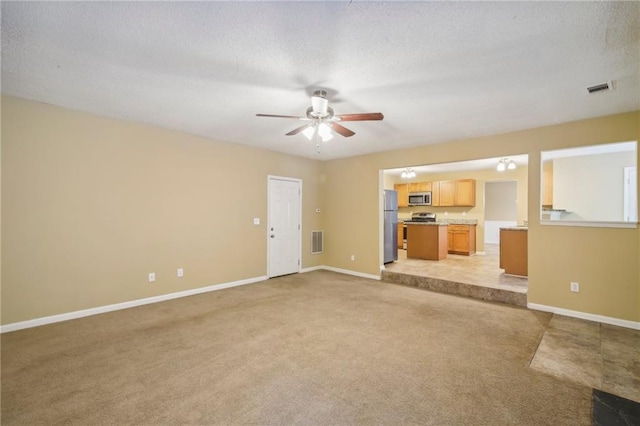 unfurnished living room featuring light carpet, a textured ceiling, and ceiling fan