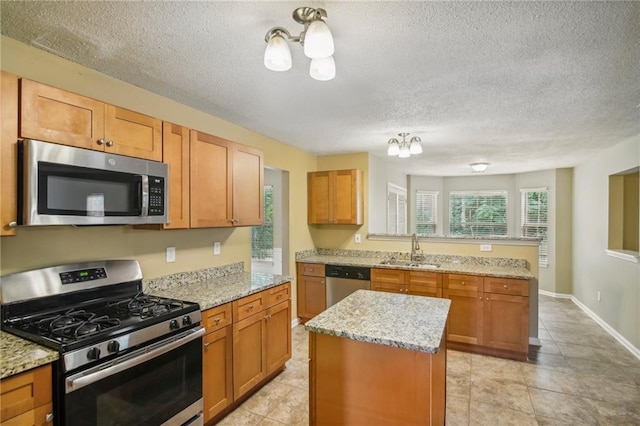 kitchen with sink, a chandelier, a center island, stainless steel appliances, and light stone countertops