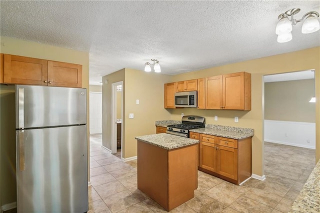 kitchen featuring light stone counters, stainless steel appliances, a kitchen island, and a textured ceiling